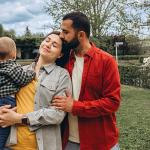 A young family of 3 spending time together outdoors in a park.