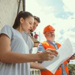A foreman showing a young couple the plans to their new home.