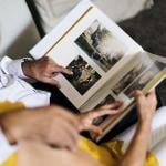 An elderly couple browsing and looking through a photo album.