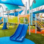 A colorful, modern playground with slides, bridge, climbing stairs, and a canopy.