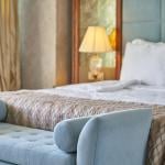 A premium bed, sofa, and bedside furniture inside a luxurious hotel room.