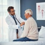 A doctor assessing an elderly person's breathing with a stethoscope during a medical check-up.
