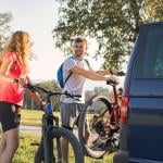A couple taking down electric mountain bikes from their van for a nature recreational adventure.