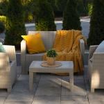 An outdoor rattan garden furniture set with yellow and cream motifs.