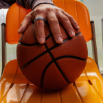 A player's hand wearing an Oura ring placed over a basketball.