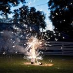 Fireworks going off at a backyard picnic during Fourth of July.
