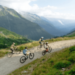 A group of e-mountain bikers riding through glacial mountains.