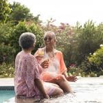 Two retired women having drinks and enjoying their time in a pool.