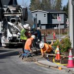  A group of construction workers smoothening a wide concrete curb.