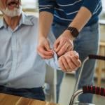 A home caregiver assisting an elderly person before checking the patient's blood pressure.
