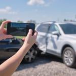 A driver taking a photo of their car's damage after an accident.