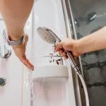 Person testing the water temperature on a shower hose.