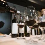 Wine being poured into glasses by a somelier at a restaurant.