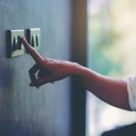 Person turning off a light switch at home.