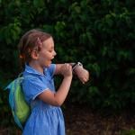 A school kid using her smartwatch outdoors in a park.