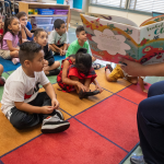 A teacher reading to small children in a classroom.
