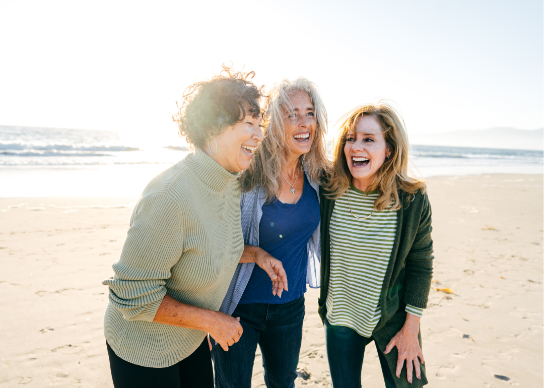 Three senior women laughing on the beach.