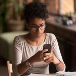 A confused woman looking at her phone.