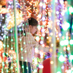 A child playing in a display of Christmas lights.