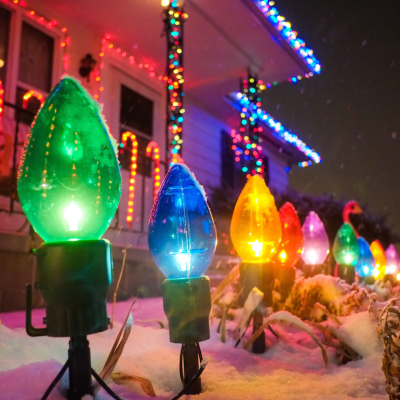Close up of colorful Christmas lights on and around a house in snow.