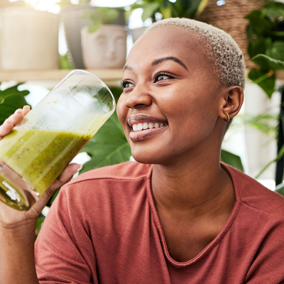 A smiling woman drinking a smoothie.