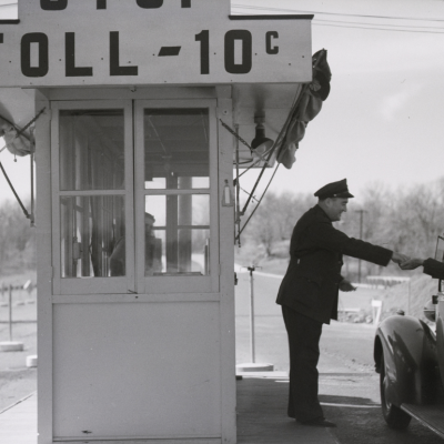 Toll collector at booth with sign