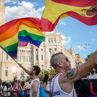 A man waves the Spanish flag and another the LGTBI+ flag in front of the Palacio de Cibeles, during the Pride March in Madrid.