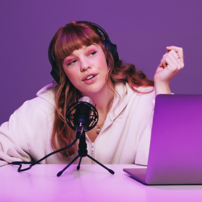 Podcaster recording an audio broadcast in neon purple light.