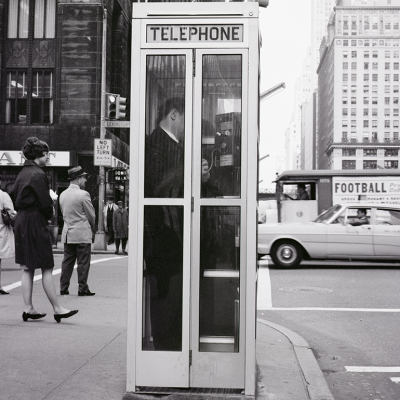 A vintage black and white photo of a telephone booth at 42nd Street and Lexington Avenue in New York City.