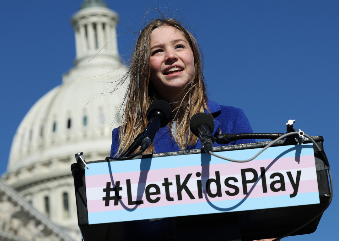 A student athlete speaks at a press conference at the U.S. Capitol. The sign on the podium says # Let Kids Play.