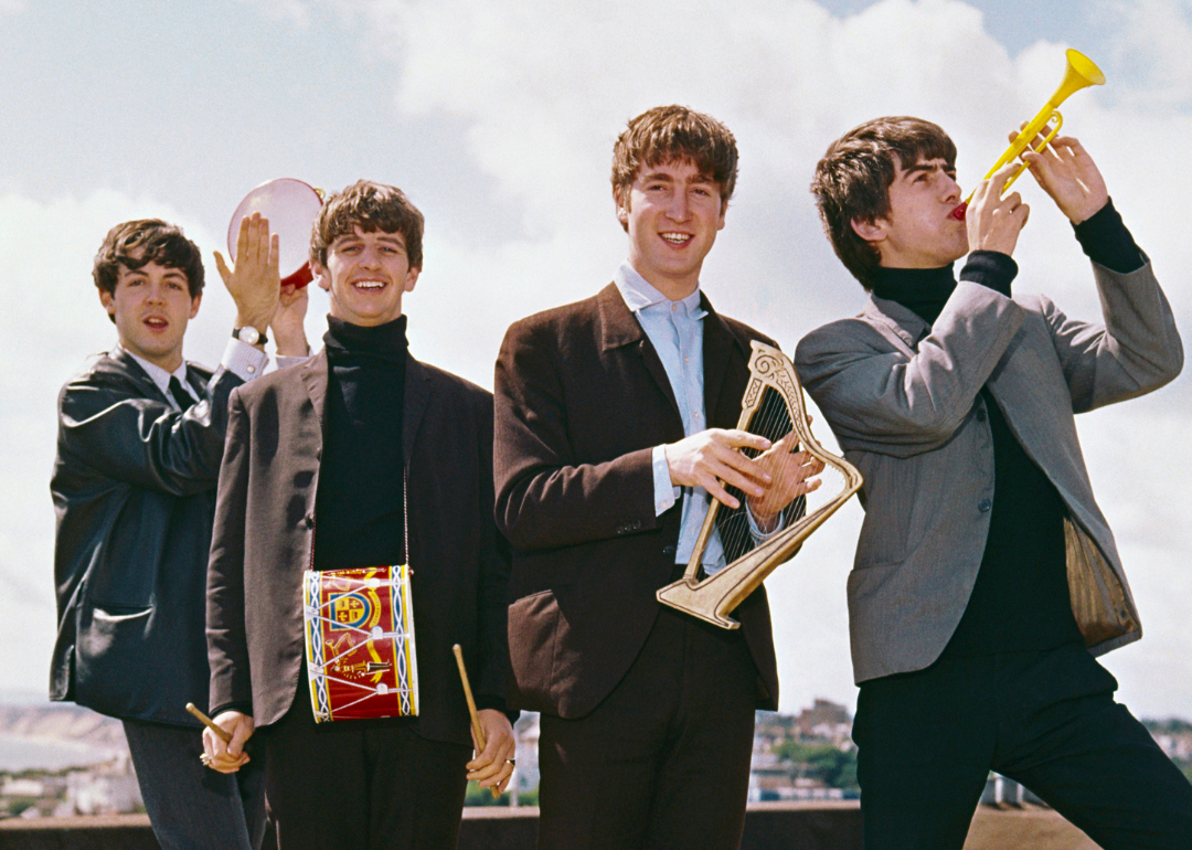 The Beatles pose for a rooftop portrait with toy instruments.