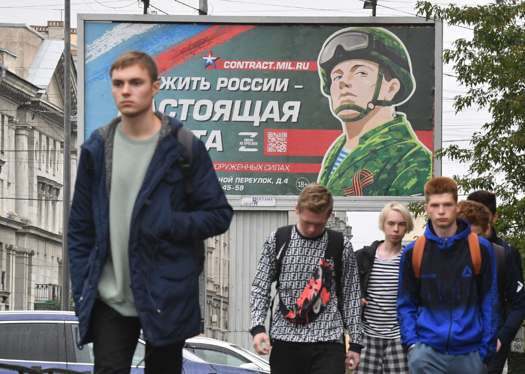 Young men walk in front of a billboard promoting army service in Saint Petersburg.