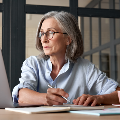 Serious mature woman looking at laptop.