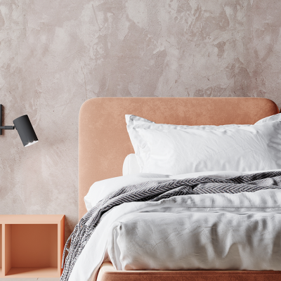 Bedroom with peach color headboard and plaster accent wall.