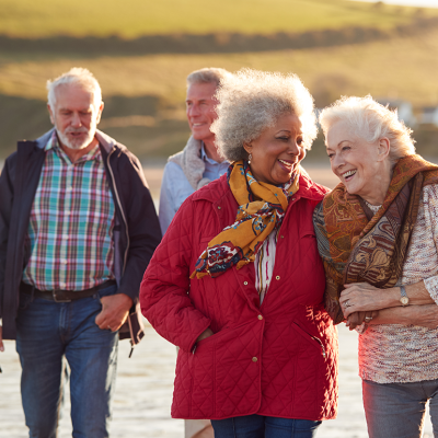 Group of smiling senior friends walking near water.