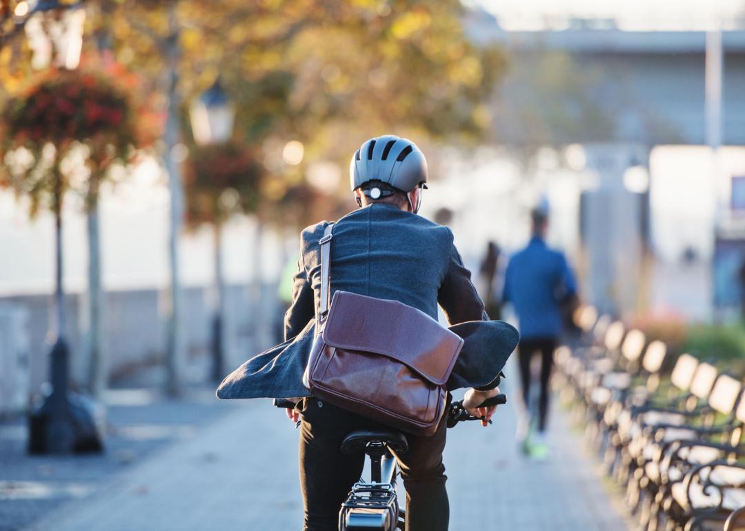 Rear view of businessman commuter with electric bicycle traveling to work