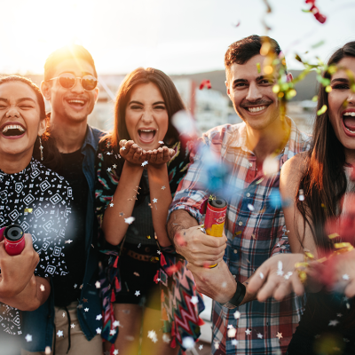 Group of friends throwing confetti on rooftop party.