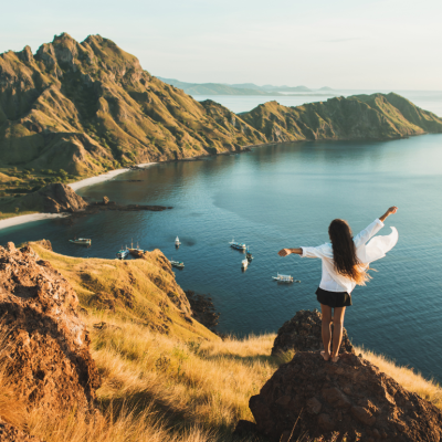 Woman standing on Padar island lookout with arms raised