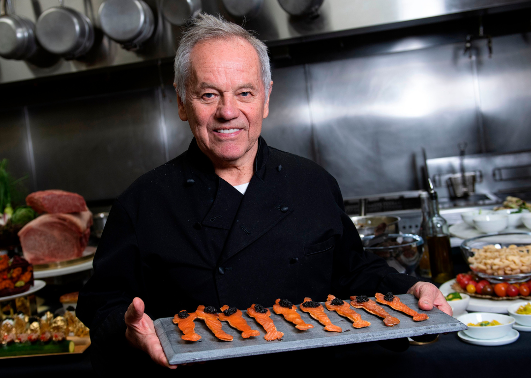 Wolfgang Puck poses in the kitchen with smoked salmon and caviar Oscar statues.