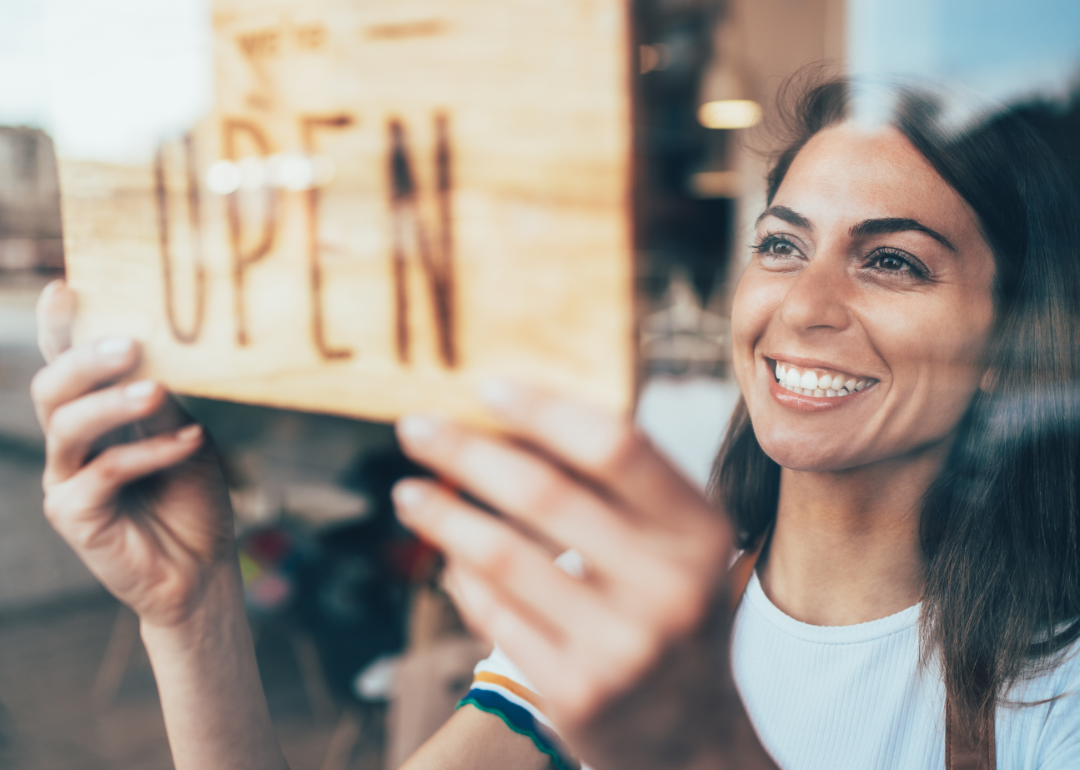 Woman placing an Open sign on her business door.