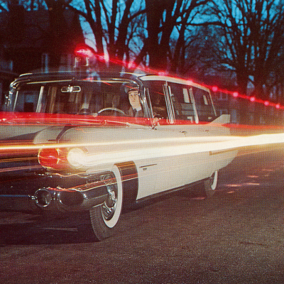Light trails from a 1950s Cadillac ambulance driving on a road.