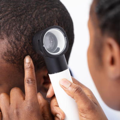 Doctor with dermatoscope checking skin on head.