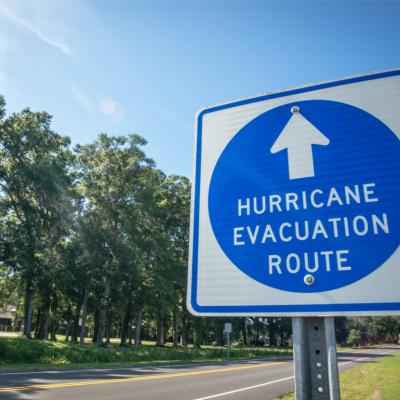 A hurricane evacuation route sign at the side of a gravel roadway.