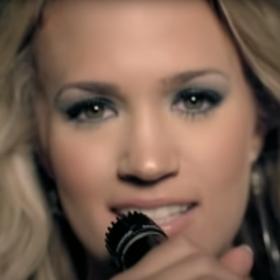 Carrie Underwood closeup holding microphone in "Before He Cheats" video