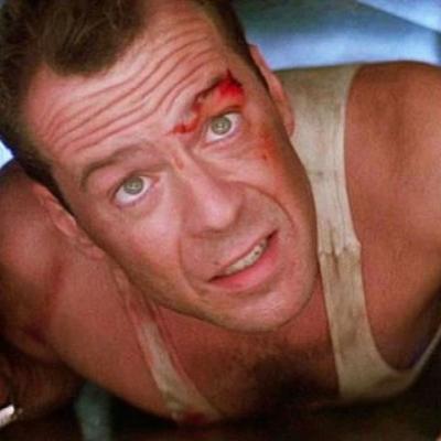 Bruce Willis in white tank top with a cut over his eye in "Die Hard"