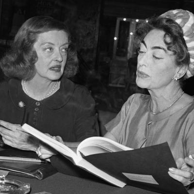 Bette Davis (left), and Joan Crawford (right), Hollywood's long reigning queens, are photographed for the first time together as they look over the script of the film, "What Ever Happened to Baby Jane?"