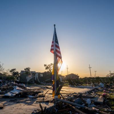The American and City of New Orleans Mardi Gras flag is seen standing in a field of tornado-damaged wreckage in the Arabi neighborhood on March 24, 2022 in New Orleans, Louisiana.