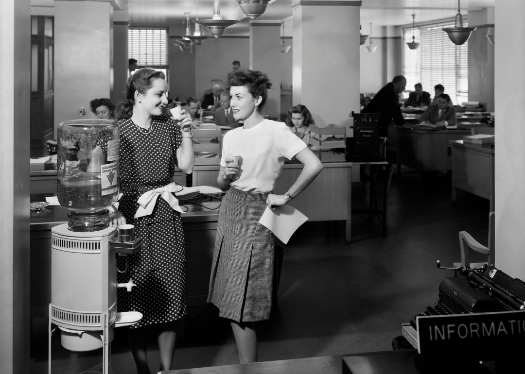 Two women chat by the office water cooler in the 1940s.