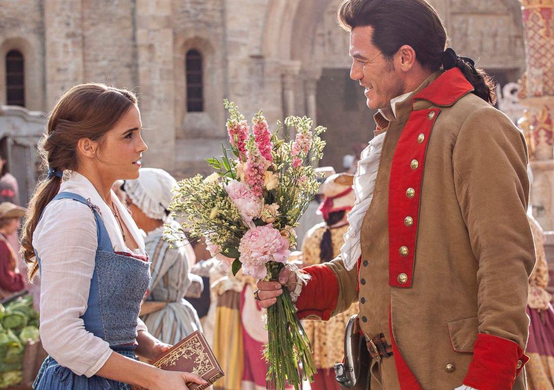Luke Evans as Gaston hands flowers to Emma Watson as Belle in the live-action "Beauty and the Beast"