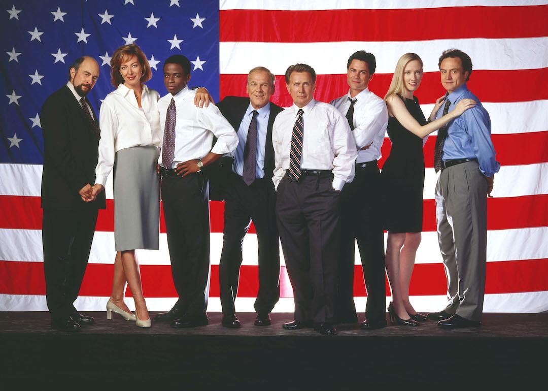 The cast of 'The West Wing' stands in front of an American flag. From left: Actors Richard Schiff, Allison Janney, Dule Hill, John Spencer, Martin Sheen, Rob Lowe, Janel Moloney, and Bradley Whitford.